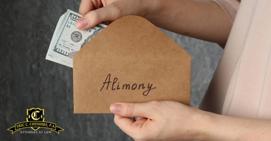 Hand placing cash into envelope labeled alimony, illustrating spousal support and financial issues in Florida divorce.